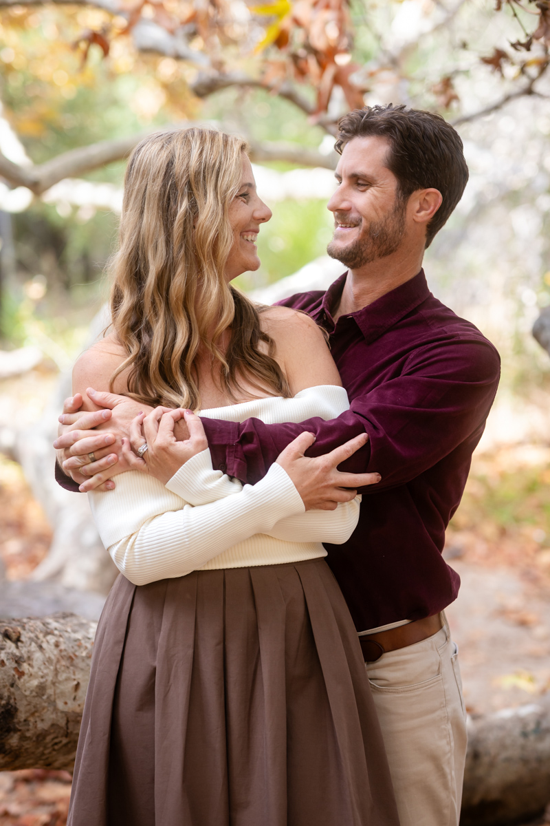 Engaged couple embracing outdoors in soft natural light