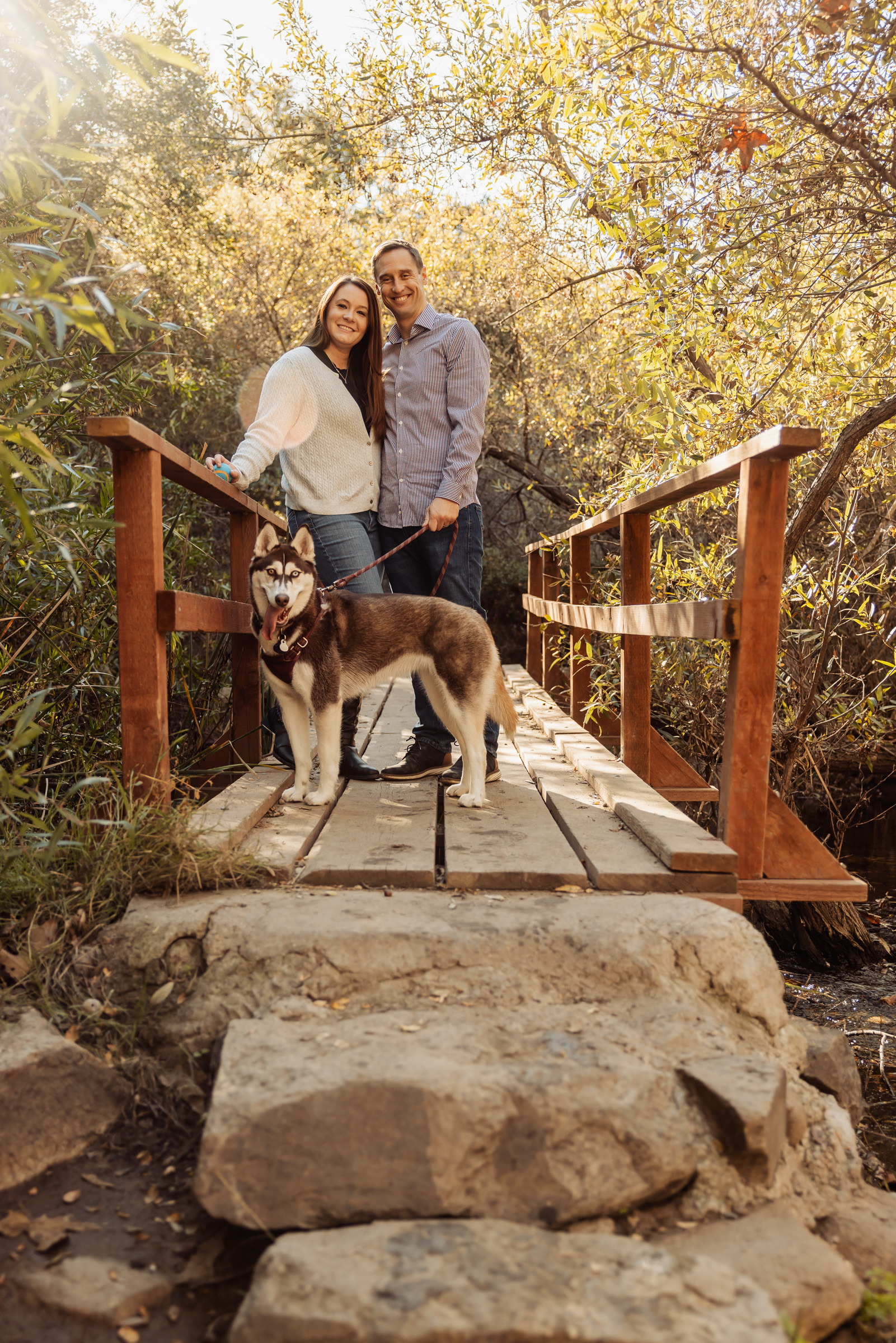Couple posing with their husky on a stone footbridge along the canyon trail in Rancho Penasquitos