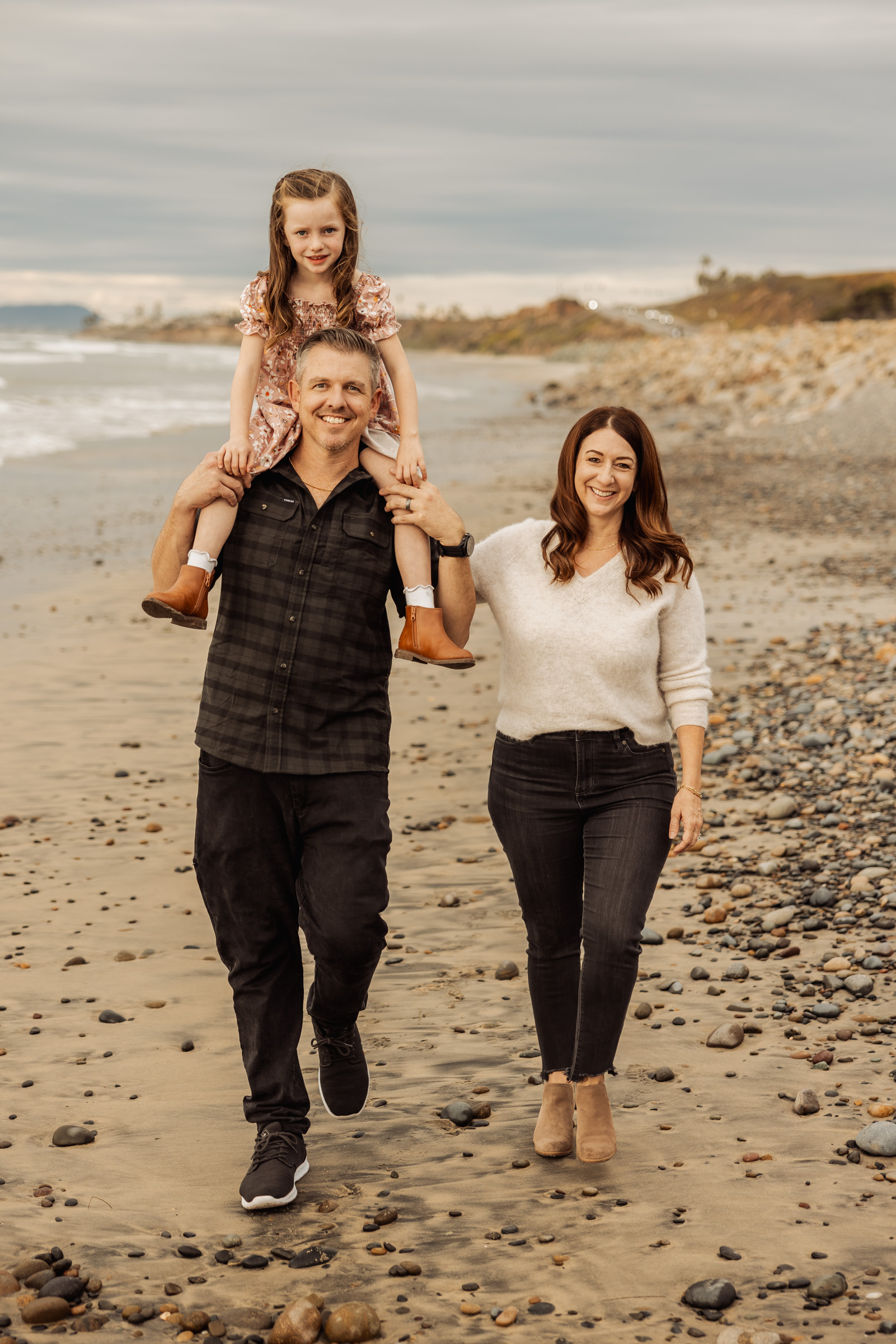 Family walking the cobble shoreline below the bluffs in Carlsbad, San Diego County