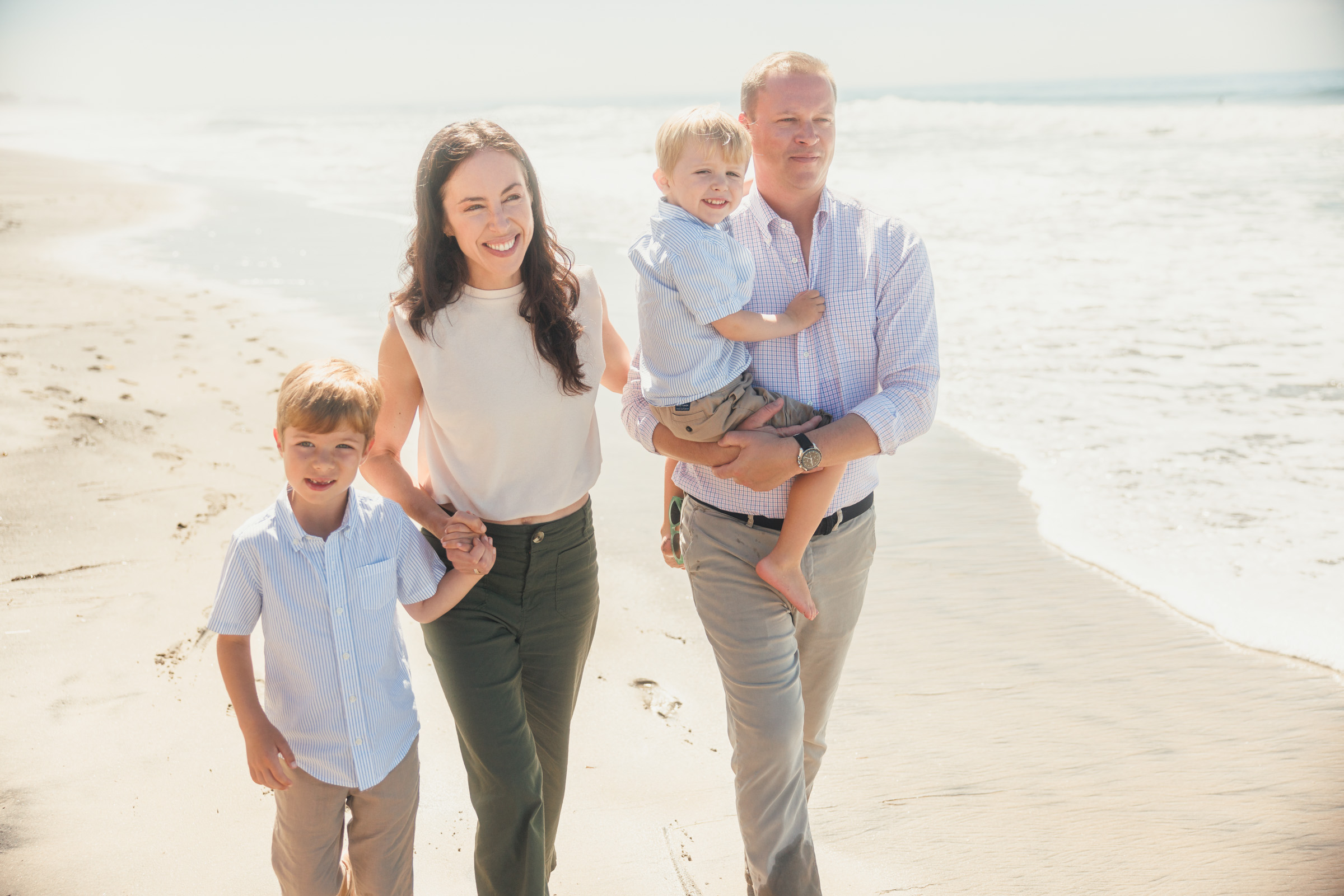 Family gathered on the beach with their new baby in Carlsbad, San Diego