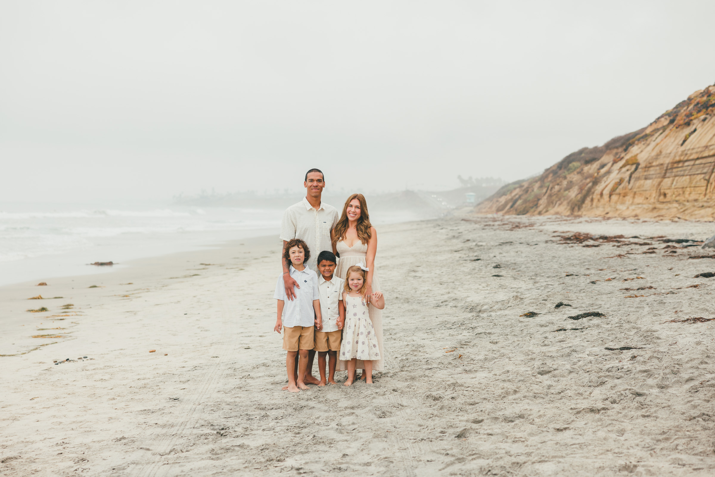 Family of five photographed on the open sand below the bluffs in Carlsbad, San Diego County