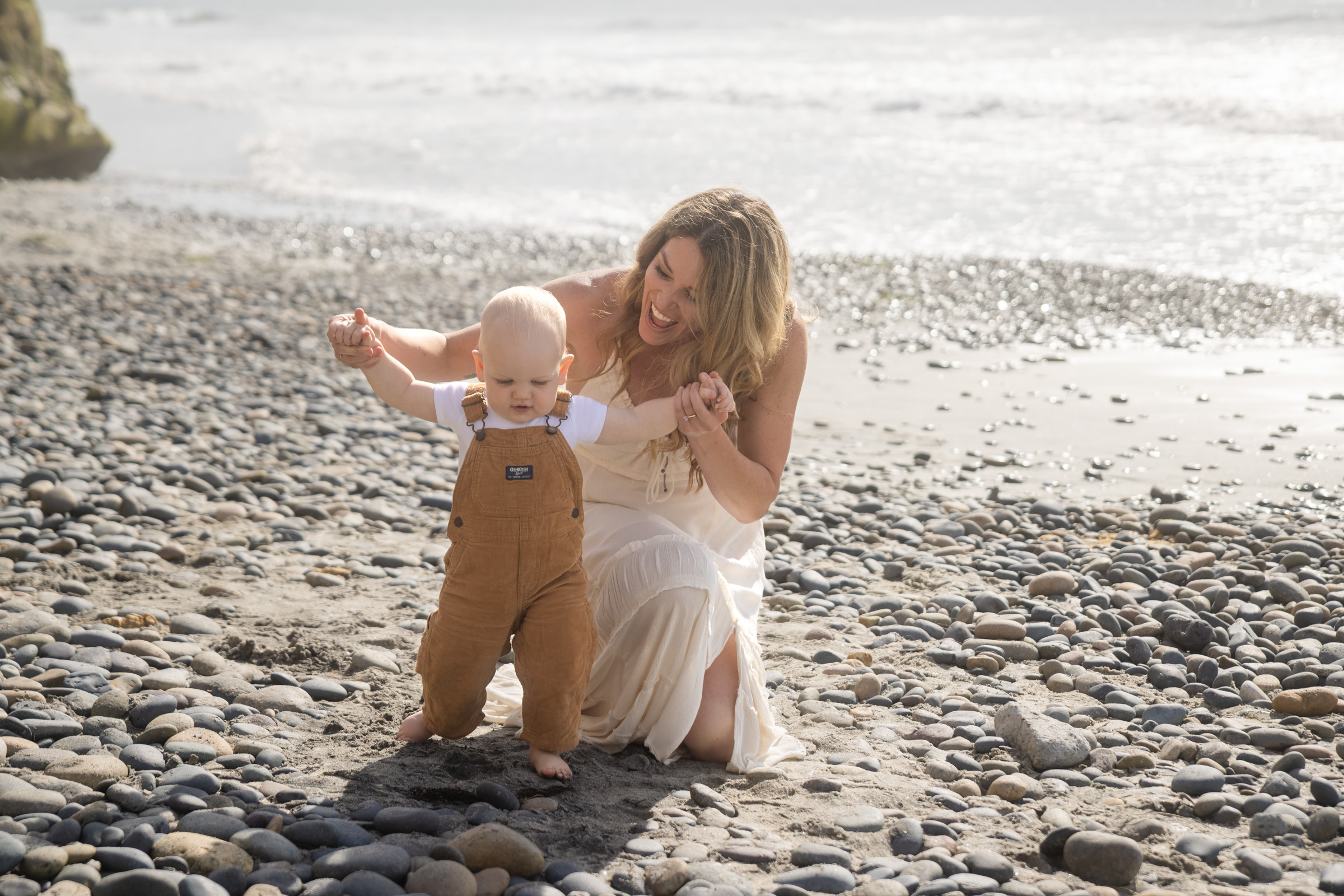 Mother and toddler on the cobble shoreline during a Carlsbad family photo session