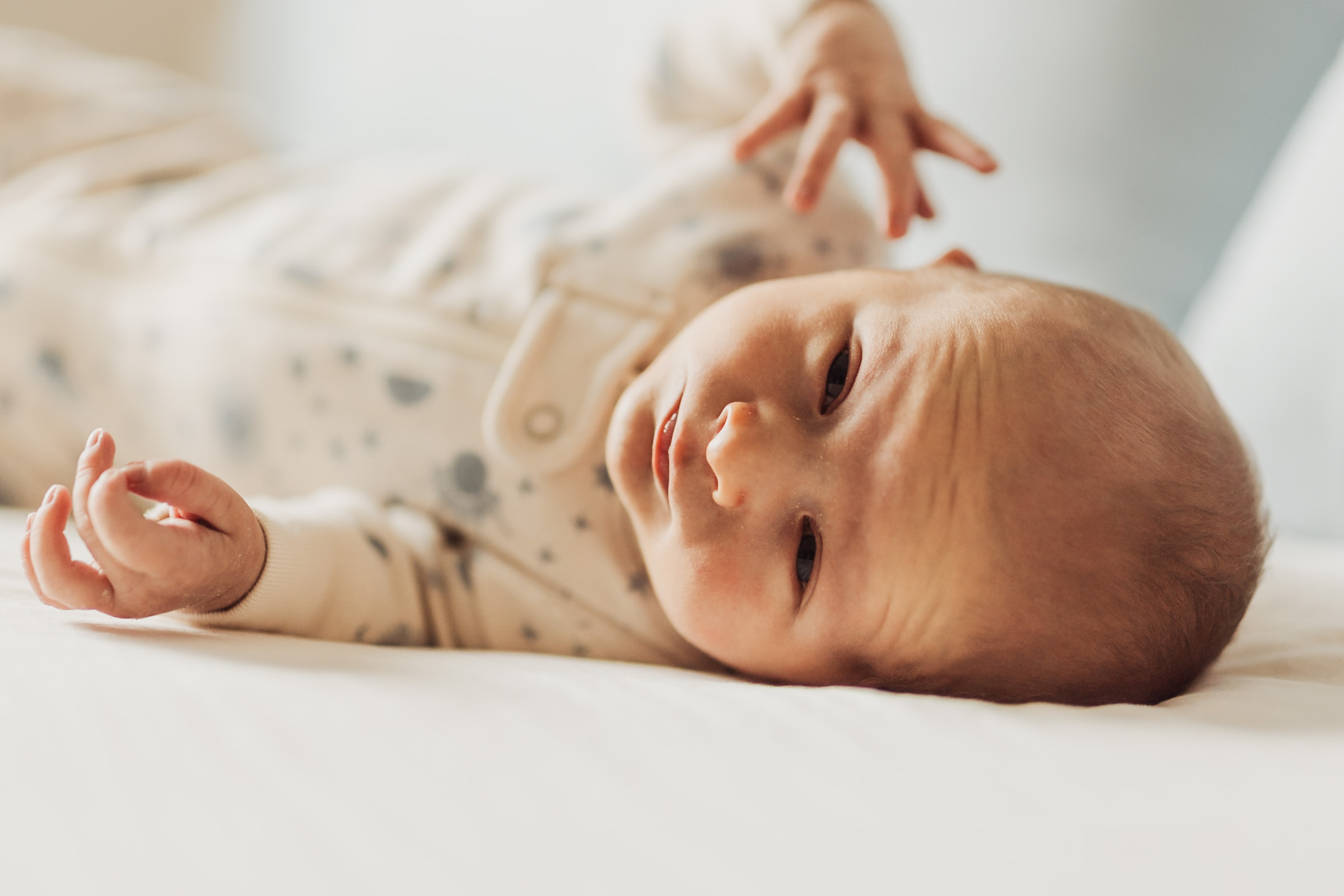 Newborn lying awake on a bed during an in-home session