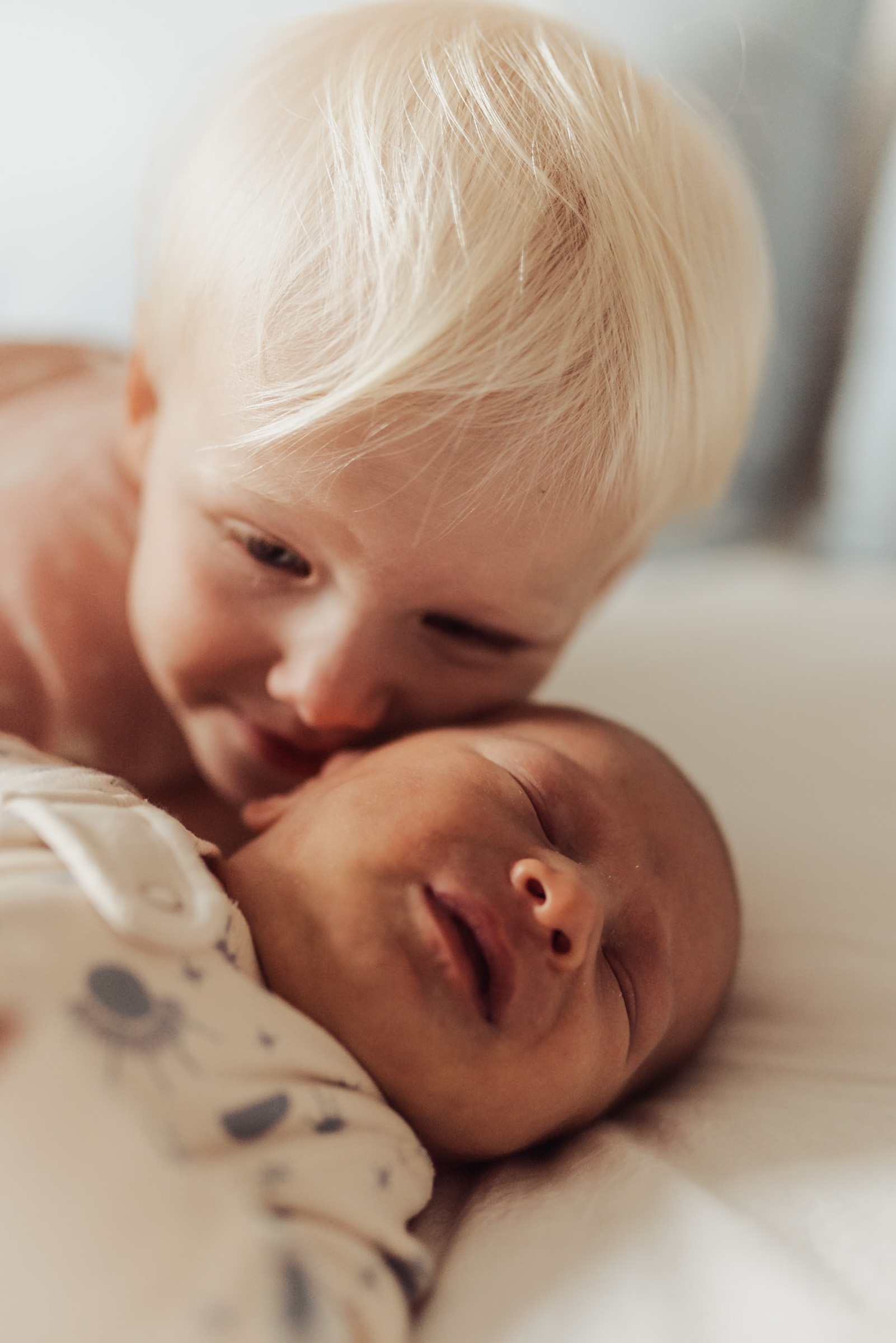 Toddler kissing a newborn sibling during an in-home newborn session