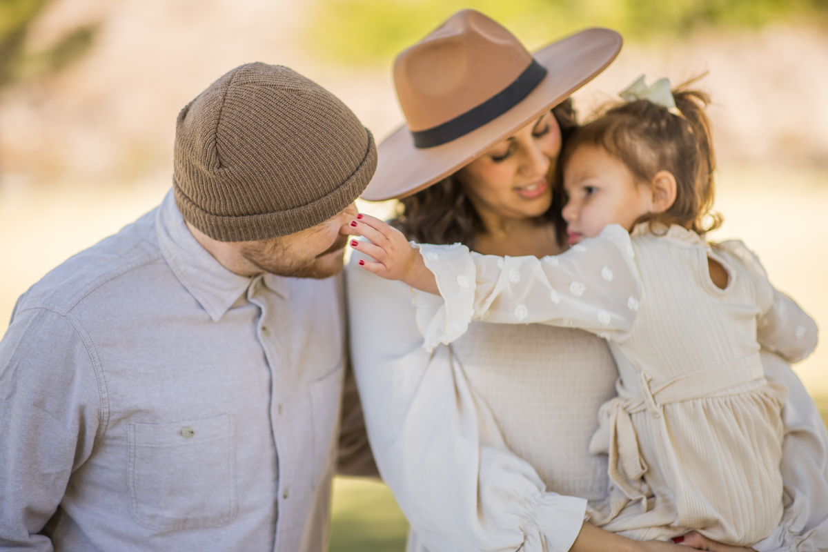 Parents holding their daughter close during an outdoor family portrait
