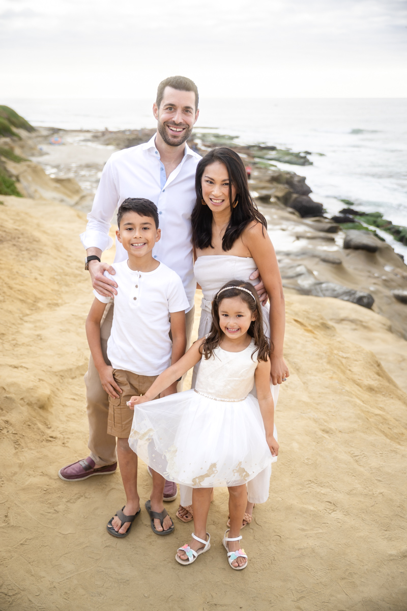 Family of four photographed on a sandy bluff overlooking the ocean
