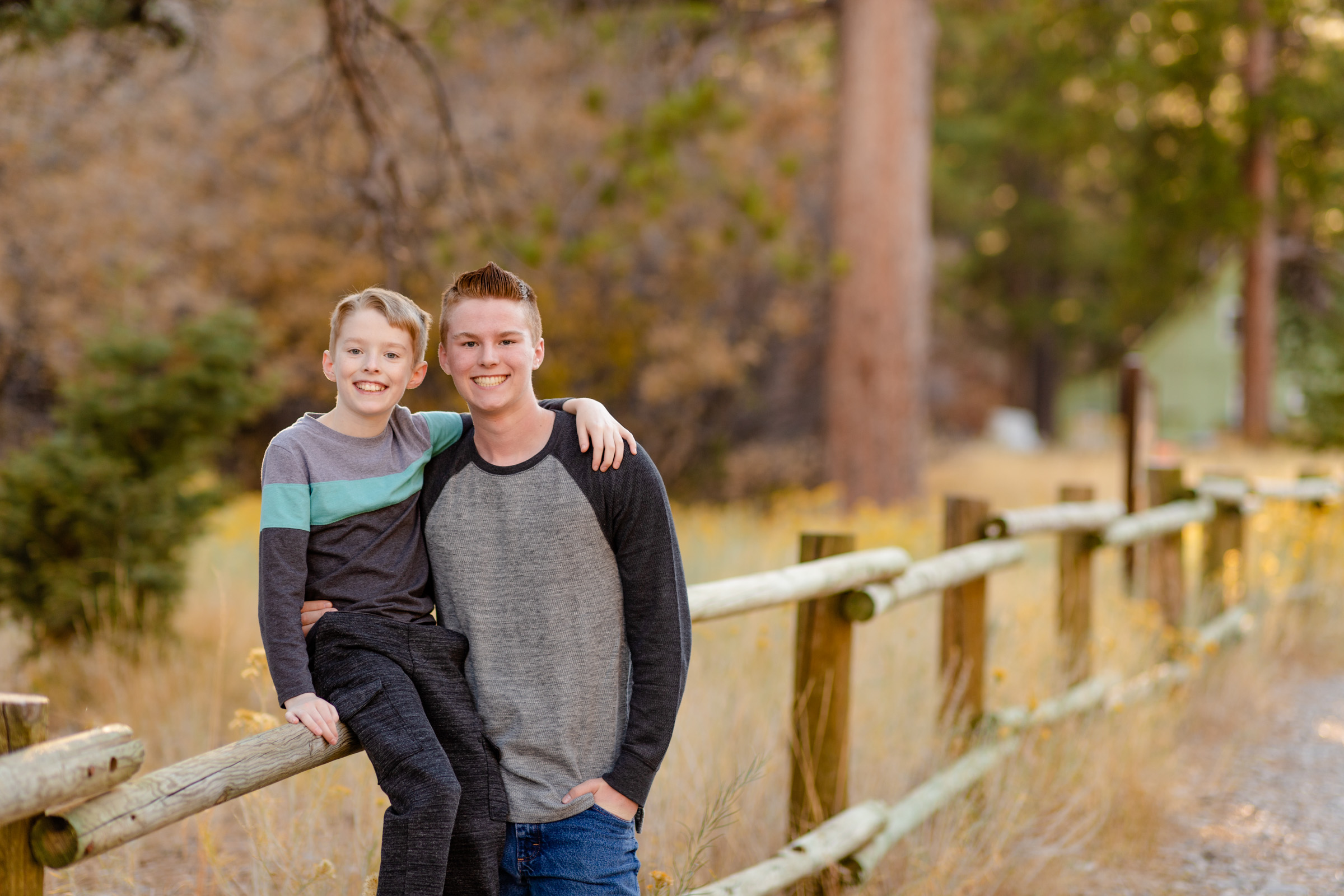 Two brothers leaning on a wooden fence in the pine forest at Mount Charleston near Las Vegas