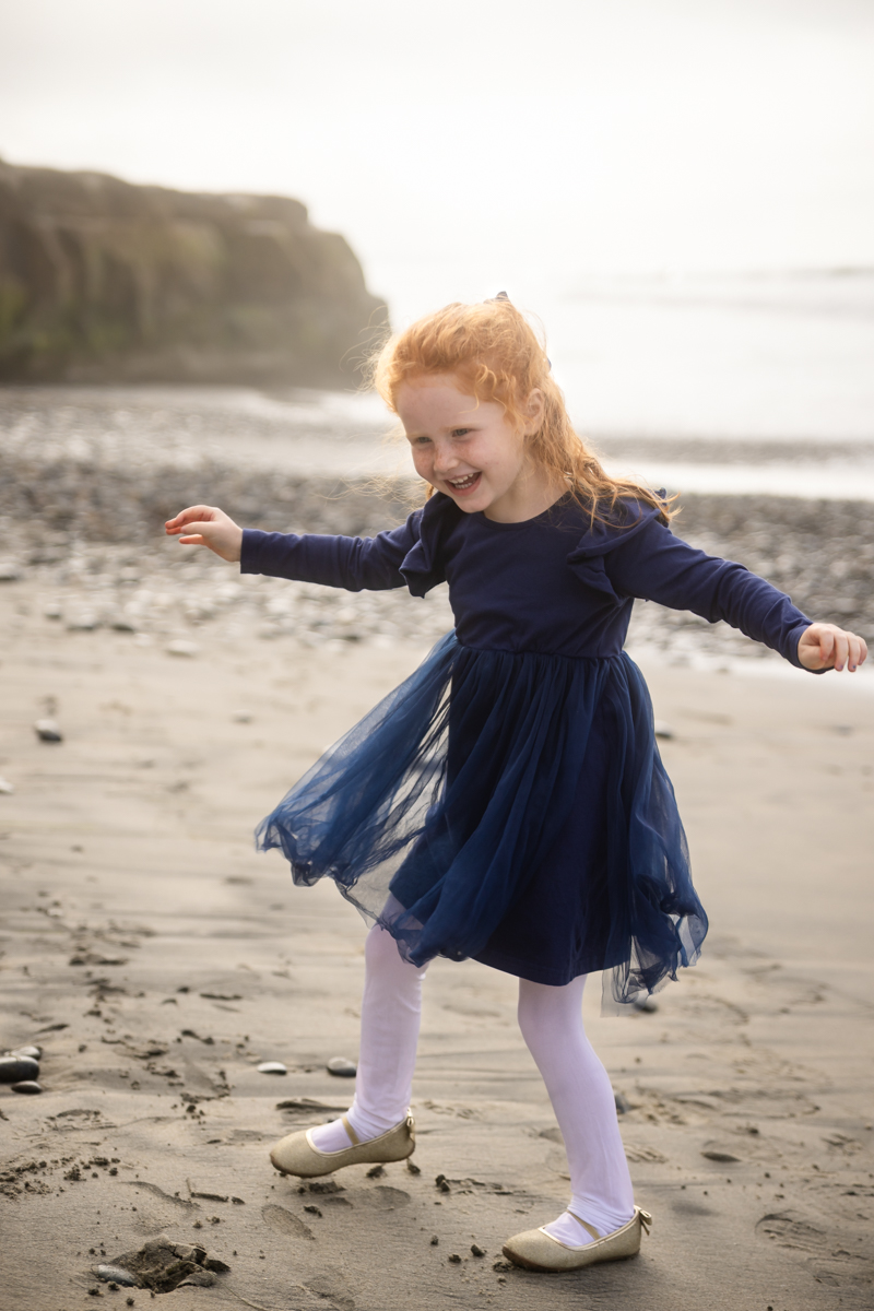 Young girl smiling with arms outstretched during a beach portrait session