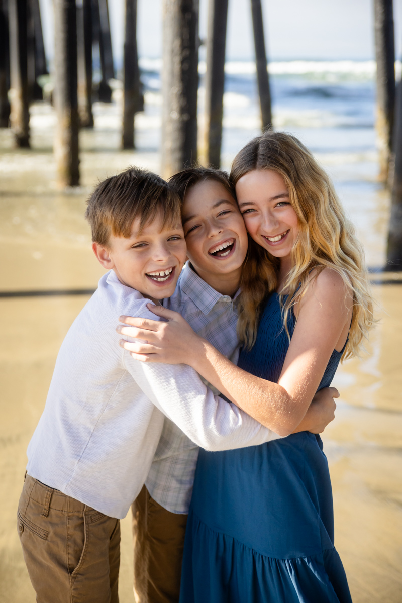 Three siblings embracing on the beach during a children’s portrait session