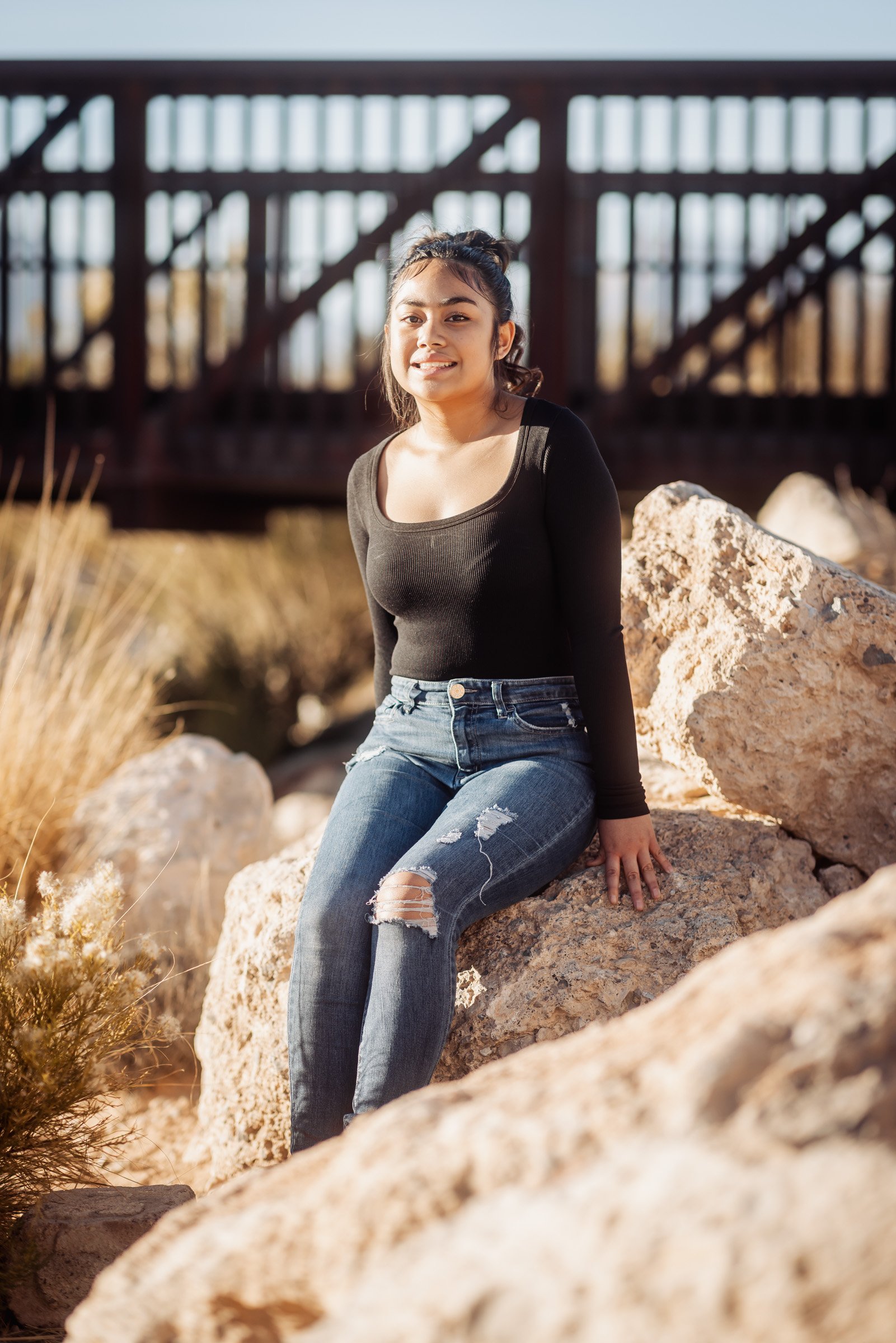 Senior portrait of a girl seated on desert boulders in Summerlin, Las Vegas
