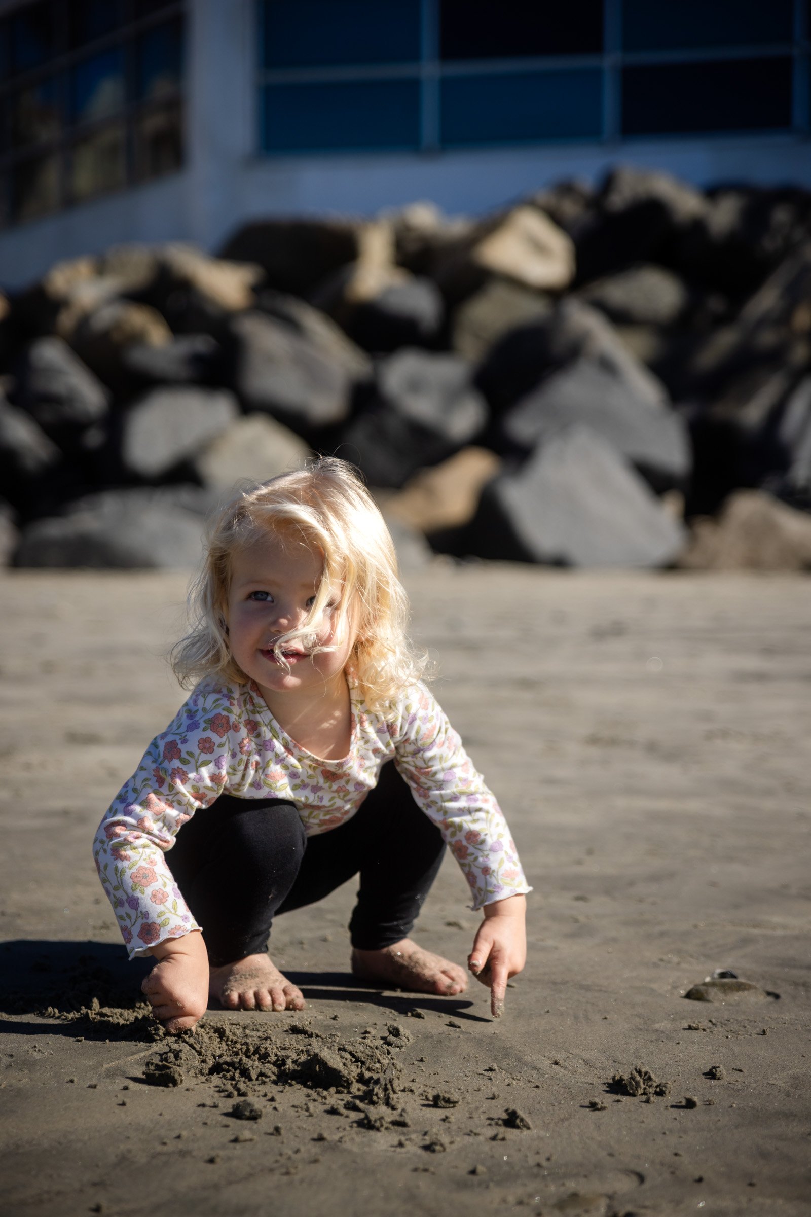 Young girl playing on the sand during an Oceanside beach photo session in San Diego County