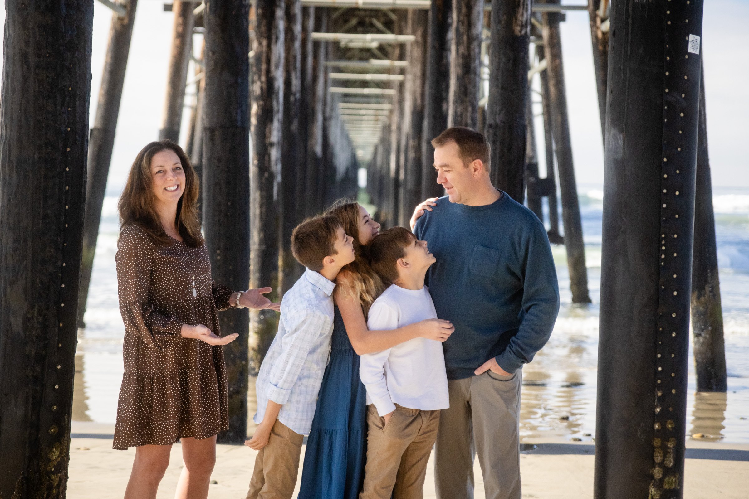 Family photographed beneath the Oceanside pier at sunset in San Diego County