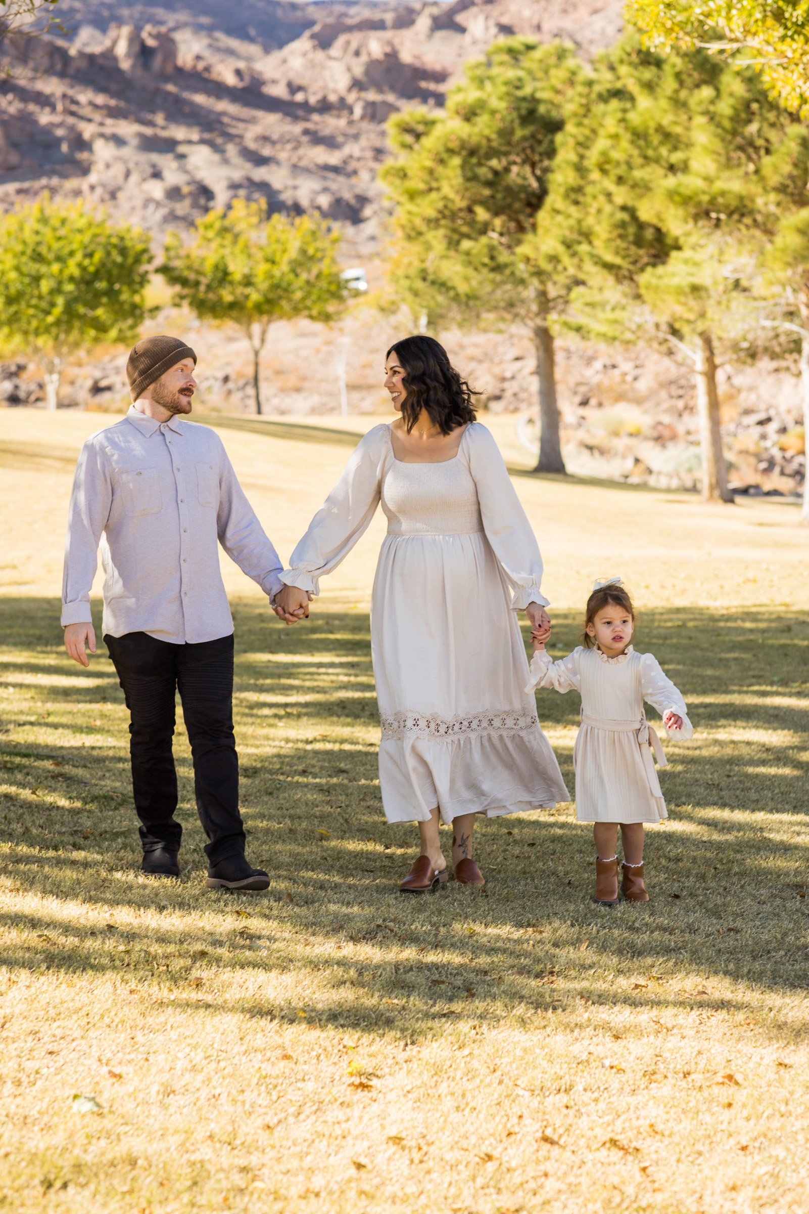Family in white walking hand in hand across a Henderson park lawn near Las Vegas