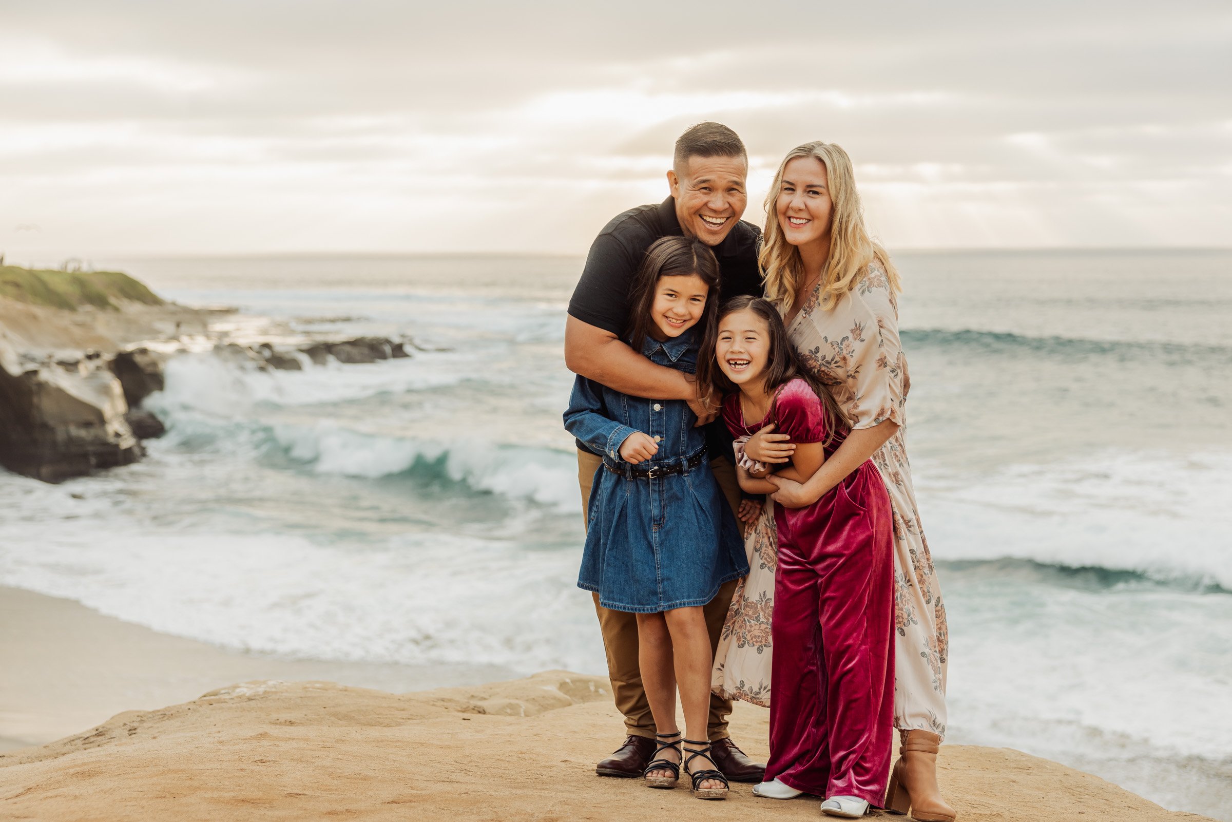 Family photographed on the sandstone bluffs above the surf at La Jolla Cove in San Diego