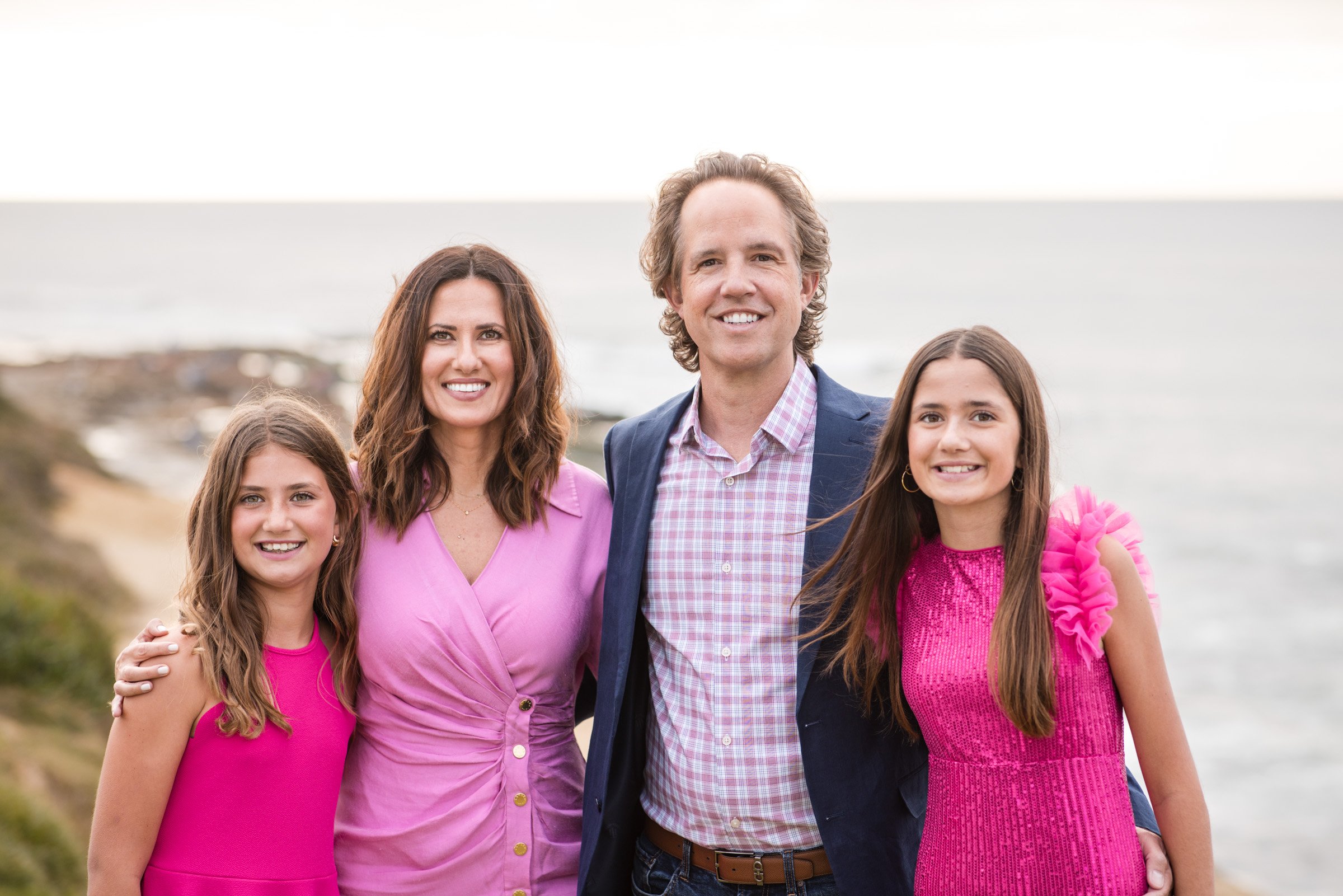 Family photographed on the sandstone above the water at La Jolla Cove in San Diego