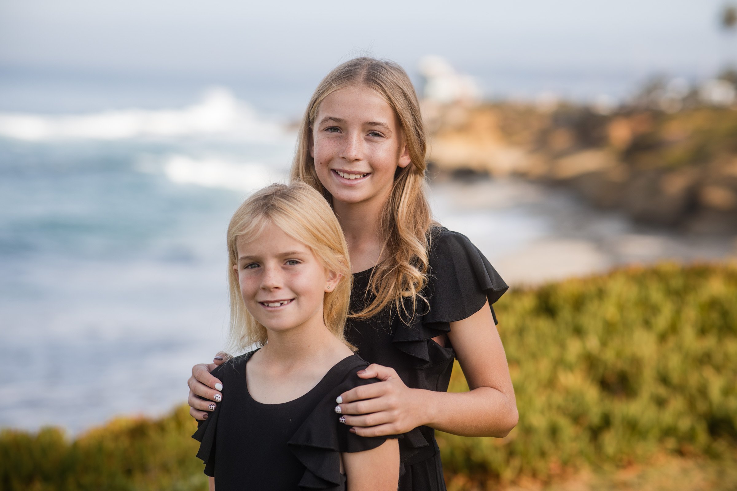 Two sisters photographed on the sandstone at La Jolla Cove during a San Diego kids session