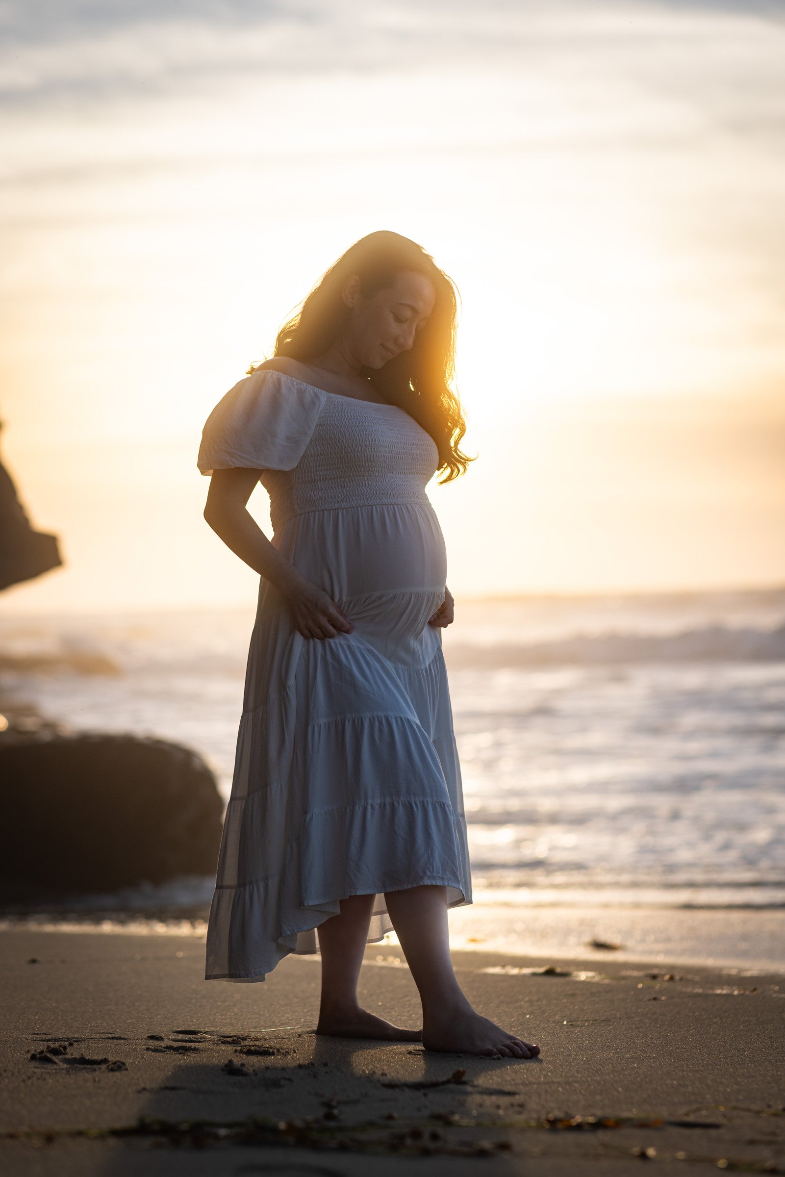 Expecting mother silhouetted against the sunset at La Jolla Cove in San Diego