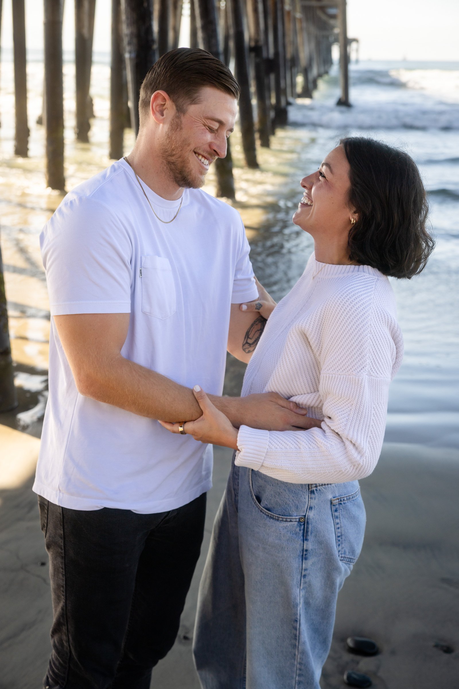 Couple photographed on the wet sand beneath the Oceanside pier in San Diego County