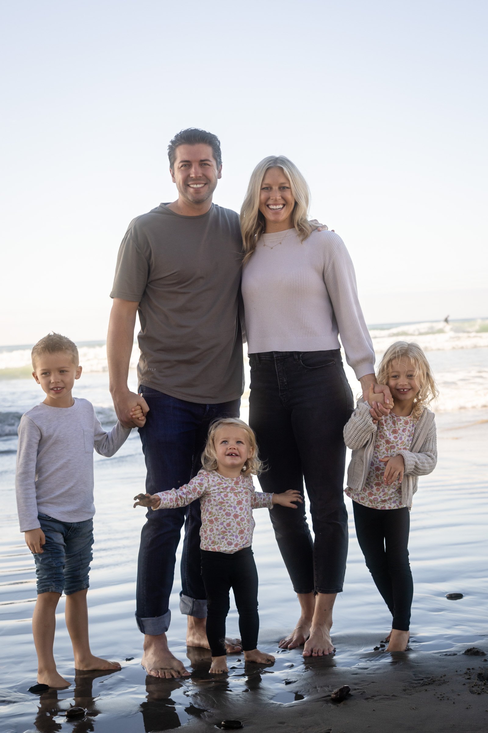 Family walking together along the shoreline at sunset in Oceanside, San Diego County